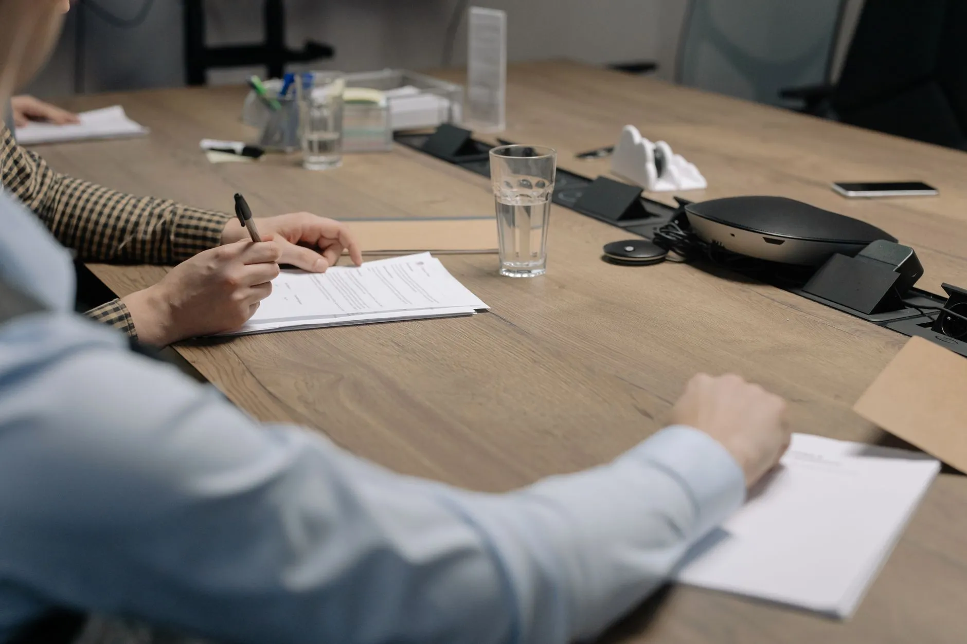 Business owner signing financial documents at desk with calculator for year-end HVAC acquisition closing