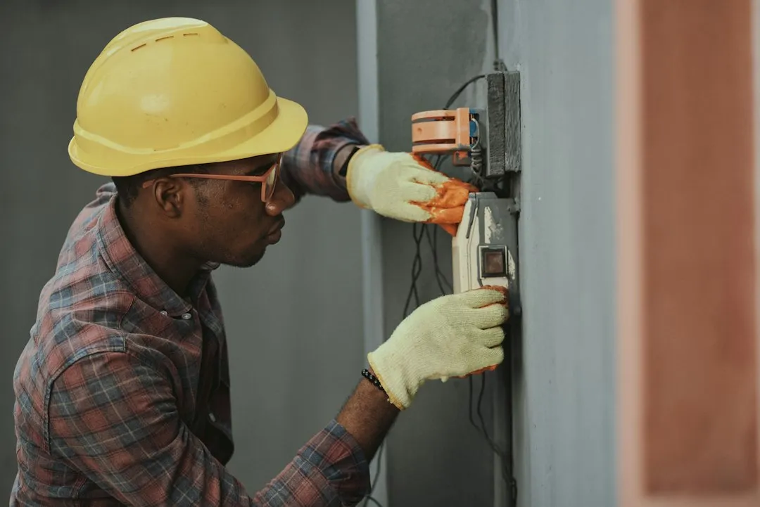 HVAC technician diagnosing residential air conditioning unit with multimeter