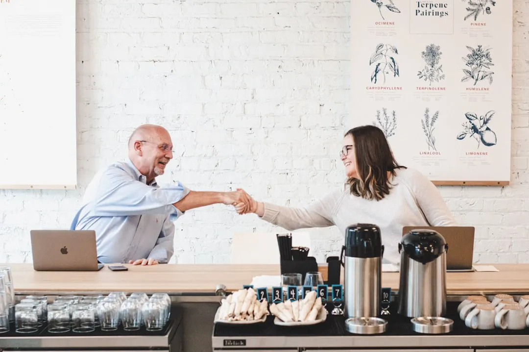 Older business owner shaking hands with a younger worker