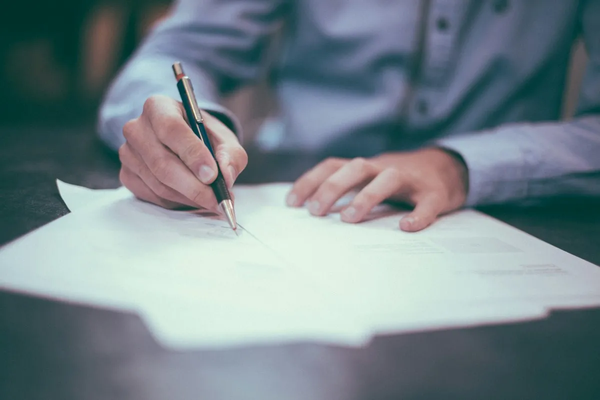 Business professionals reviewing and signing franchise transfer documents at a meeting table