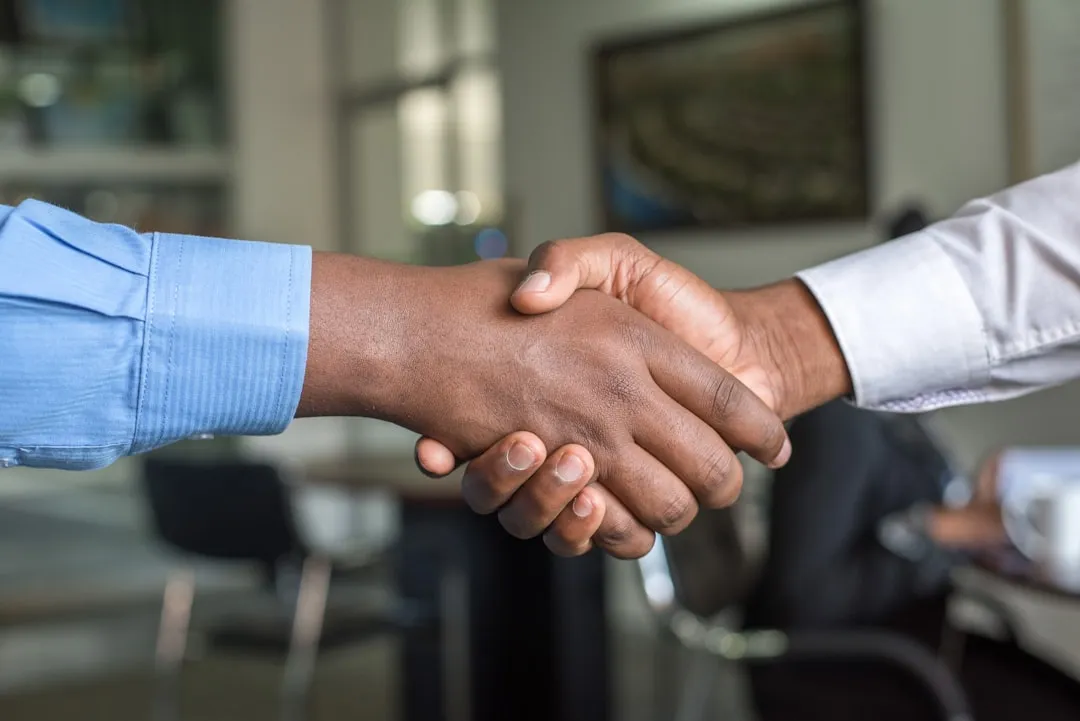 Business succession handshake — ownership transfer between experienced and new generation